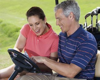 a couple sitting in a golf cart looking at a scorecard together